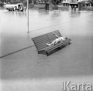 Sierpień 1962, Sandomierz, Polska. 
Międzynarodowy Obóz Studencki, dziewczyna w bikini opala się na ławce stojącej na placu zalanym wodą.
Fot. Romuald Broniarek/KARTA
