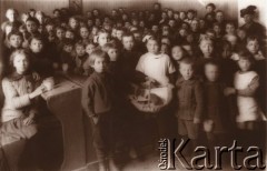 1915, Lwów, Austro-Węgry.
Duża grupa dzieci w klasie (sierociniec?), dziewczynka w środku trzyma kosz z chlebem.
Fot. NN, zbiory Ośrodka KARTA, udostępnił Jurij Karpenczuk