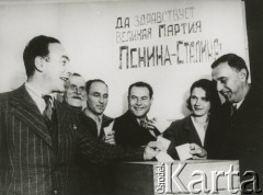 1939-1940, brak miejsca.
Wyborcy przy urnie, na ścianie wisi hasło: 