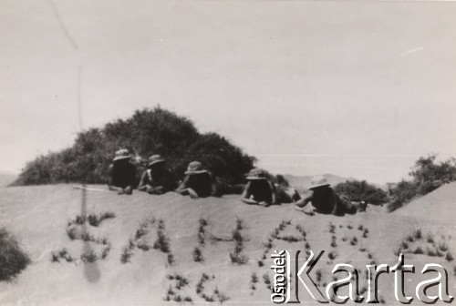 Kwiecień 1942, Sahara.
Samodzielna Brygada Strzelców Karpackich - żołnierze odpoczywają na pustynnym piasku. Na pierwszym planie widoczny jest również - utworzony z kęp trawy - napis: 