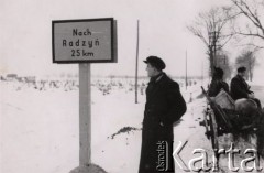 1940-1944, Radzyń Podlaski, woj. Lublin, Polska.
Konny wóz na drodze do Radzynia, mężczyzna stojący obok niemieckiego drogowskazu 