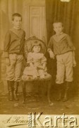 Ok. 1895, Psków, Rosja.
Portret rodzinny: bracia Jerzy (od lewej) i Władysław Kobylańscy, na krześle siedzi siostra Aniela Kobylańska. Chłopcy ubrani są w bluzy i buty z wysokimi cholewami. Podpis na odwrocie: 