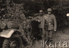 1940, Francja.
 Dwaj żołnierze - sierżant Wehrmachtu odznaczony Krzyżem Żelaznym i sznurem nagrodowym, z przymocowaną do pasa torbą meldunkową oraz kaburą na pistolet P08 i szeregowy Wehrmachtu. Żołnierze stoją przy zamaskowanym gałęziami samochodzie sztabowym Kraftfahrzeug 15 (Mercedes-Benz 340).
 Fot. NN, zbiory Ośrodka KARTA, udostępnił Stanisław Blichiewicz
   
