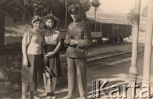 1940, Niemcy.
 Plutonowy Wehrmachtu i dwie kobiety na stacji kolejowej, w tle pociąg towarowy.
 Fot. NN, zbiory Ośrodka KARTA, udostępnił Stanisław Blichiewicz
   
