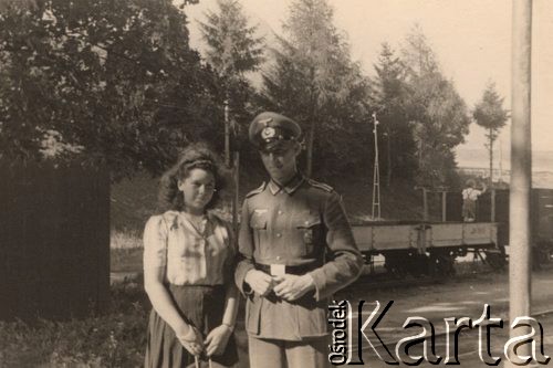 1940, Niemcy
 Plutonowy Wehrmachtu z dziewczyną na stacji kolejowej, za nimi pociąg towarowy.
 Fot. NN, zbiory Ośrodka KARTA, udostępnił Stanisław Blichiewicz
   
