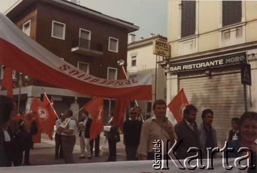 Lata 80., Włochy.
Pierwszomajowa demonstracja zorganizowana przez włoskie związki zawodowe - manifestanci z polską flagą, na której widoczny jest napis: 