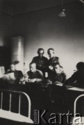 Brak daty, brak miejsca.
Grupa żołnierzy siedząca przy stole w garnizonie wojskowym. Na pierwszym planie widoczne są łóżka. 
Fot. Józef Tarań, zbiory Ośrodka KARTA, kolekcję zdjęć przekazała Lucyna Kumiszczo