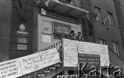 Maj (?) 1981, Warszawa, Polska
Protest pracowników SKR-ów. Na balkonie plakaty z napisami: „Fergurson bankrutował, rząd go uratował, on się z tego śmieje, Ursus nam rdzewieje”; „Hej kochany nasz premierze. Pomyśl też o SKR-ze”; „Pracownicy SKR nie żądają nic więcej, tylko tyle ile im się należy”; „Nie chcemy być smutnym końcem rolnictwa”; „Będzie płaca sprawiedliwa. Będą na wsi sprawne żniwa”; „Chcemy być w pierwszym szeregu odnowicieli polskiego rolnictwa”; „Generale nasz kochany zrób porządek z doradcami, daj nam wszystko to co trzeba, my zaś damy więcej chleba”; „Żądamy natychmiastowego podpisania protokołu VB12 do układu zbiorowego pracy”; „Malinowski u Premiera postulaty SKR-u popiera”. Nad drzwiami tablica Związek Zawodowy Pracowników Rolnictwa w PRL. Zarząd Główny” i transparent: „Centralny sztab ogólnopolskiej akcji protestacyjnej pracowników spółdzielni kółek rolniczych”. 
Fot. Lech Ścibor-Rylski, zbiory Ośrodka KARTA/Independent Polish Agency (IPA), przekazał Józef Lebenbaum