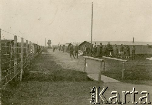 1917, Szczypiorno k/Kalisza, Polska.
Niemiecki obóz dla internowanych jeńców wojennych - polskich legionistów w Szczypiornie. Żołnierze na głównej ulicy obozu i przy barakach, po lewej ogrodzenie, w oddali wartownia. Podpis na zdjęciu: 