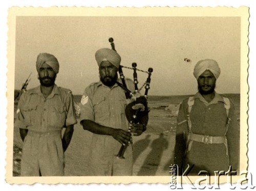 Maj 1942, Palestyna.
Trzej hinduscy żołnierze, w środku stoi kobziarz grający na kobzie.
Fot. Czesław Dobrecki, zbiory Ośrodka KARTA, Pogotowie Archiwalne [PAF_015], przekazał Krzysztof Dobrecki