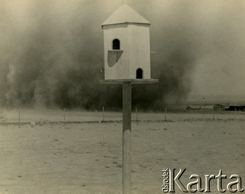 Lipiec 1943, Irak.
Drewniana budka, prawdopodobnie dla ptaków, w tle: trąba powietrzna. Oryginalny podpis na odwrocie fotografii: 