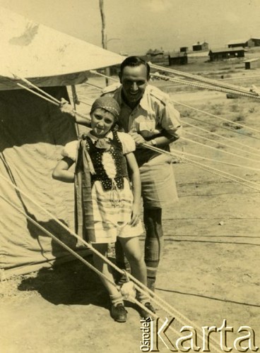 Lipiec 1942, Palestyna.
Czesław Dobrecki z dziewczynką ubraną w tradycyjny strój krakowski. Oryginalny podpis na odwrocie fotografii: 