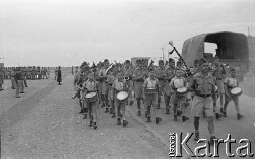 11.11.1942, Qizil Ribat, Irak.
Orkiestra podczas defilady, na pierwszym planie kapelmistrz oraz junacy z bębnami. Oryginalny podpis na odwrocie fotografii: 