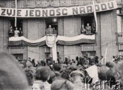 1945, Polska.
Prawdopodobnie Ziemie Odzyskane, tłum zgromadzony na wiecu. Balkon budynku, z którego jest wygłaszane przemówienie, jest ozdobiony biało-czerwoną flagą i godłem - Orłem bez korony, wyżej wisi hasło: 