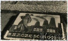 1940, Comisani, Rumunia.
Obóz internowania dla żołnierzy Wojska Polskiego, mozaika przed barakiem - męska sylwetka z młotem na tle budynku fabryki z dymiącymi kominami, napis: 