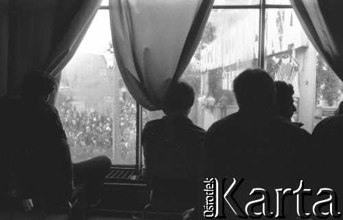 Sierpień 1980, Gdańsk, Polska.
Strajk okupacyjny w Stoczni Gdańskiej im. Lenina. Strajkujący stoją przy oknie, obserwują zgromadzony przed stocznią tłum.
Fot. Zbigniew Trybek, zbiory Ośrodka KARTA


