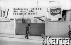 1981, Kraków, Polska.
Mężczyzna idzie obok tablicy z napisem: 