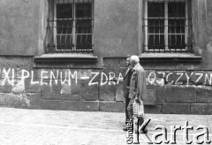 1981, Kraków, Polska.
Mężczyźni przechodzą obok napisu na murze: 