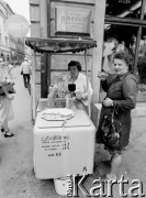 1982, Kraków, Polska.
Kobieta pije wodę sodową z saturatora. W głębi zdjęcia sprzedawczyni i tablica z napisem: 