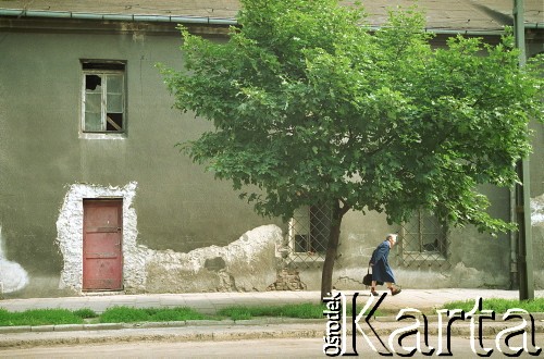 1993, Kraków, Polska.
Krakowski Kazimierz - staruszka przechodzi obok zniszczonej kamienicy. Na pierwszym planie drzewo.
Fot. Jerzy Szot, zbiory Ośrodka KARTA
