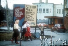 1982, Kraków, Polska.
Kobiety i dzieci przechodzą przy propagandowych plakatach z hasłami: 
