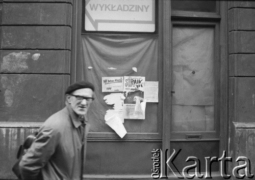 1989 , Kraków, Polska.
Mężczyzna przed okami budynku, na których zawieszono plakaty z hasłami : 