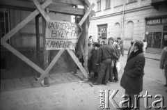 1989, Kraków, Polska.
Grupka mężczyzn  stłoczona wokół plakatu z hasłem 