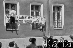 1988, Gdańsk, Polska.
Parafia pw. św. Brygidy. Mężczyźni zawieszają na budynku plebanii transparent o treści: 