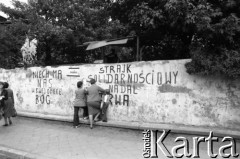 Sierpień 1980, Gdańsk, Polska.
Strajk w Stoczni Gdańskiej im. Lenina. Kobiety z dzieckiem przy murze otaczającym stocznię. Na murze napisy: 
