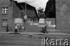 Sierpień 1980, Gdańsk, Polska.
Strajk w Stoczni Gdańskiej im. Lenina. Stoczniowcy siedzą na murze, na którym widnieją napisy: 