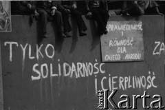 Sierpień 1980, Gdańsk, Polska.
Strajk w Stoczni Gdańskiej im. Lenina. Na murze otaczającym stocznię siedzą strajkujący, poniżej hasła: 