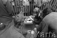 Sierpień 1980, Gdańsk, Polska.
Strajk w Stoczni Gdańskiej im. Lenina. Robotnicy klęczą przy krześle, jeden z mężczyzn przegląda fotografie.
Fot. Witold Górka, zbiory Ośrodka KARTA