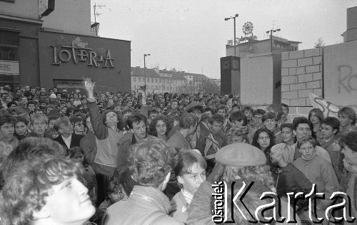 21.10.1988, Wrocław, Polska.
Happening Pomarańczowej Alternatywy na ulicy Świdnickiej – Domek na Świdnickiej. Tłum przy murze słucha koncertu zespołu. Aleksander Żebrowski unosi dłoń.
Fot. Mieczysław Michalak, zbiory Ośrodka KARTA
