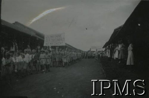 1943-1947, prawdopodobnie Valivade, Indie.
Uroczystość w osiedlu dla polskich uchodźców. W pochodzie uczestniczą dzieci, harcerze niosą transparent o treści: 