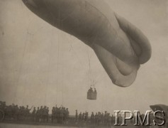 Ok. 1919, Poznań, Polska.
Wzlot balonu obserwacyjnego „Caquot R”. „Caquot R” był wojskowym balonem obserwacyjnym na uwięzi, zaprojektowanym w 1918 r. przez mjr. Alberta Caquot. Powstał w wyniku udoskonalenia poprzedniego balonu „Caquot M”. Miał 25,5 m długości i objętość całkowitą 930 m³. Pod koniec 1919 r. pierwsze balony tego typu trafiły na wyposażenie polskich batalionów balonowych. Po wojnie polsko-radzieckiej zrezygnowano z wyposażania balonów w karabiny maszynowe ze względu na małą celność osiąganą w rozchybotanym koszu. Obronę przeciwlotniczą zapewniano dzięki karabinom maszynowym ustawianym na naziemnych stanowiskach. W czerwcu 1925 r. w Centralnym Zakładzie Balonowym ukończono budowę, na licencji francuskiej, pierwszego polskiego balonu obserwacyjnego „Caquot R”. 
Album balonowowy - fotografie po dr Niedźwierskim.
Fot. NN, Instytut Polski im. Gen. Sikorskiego w Londynie