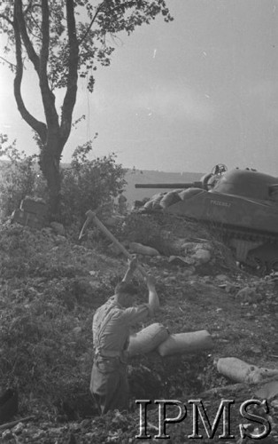Maj 1944, Cassino, Włochy.
Bitwa pod Monte Cassino, okopujący się żołnierz 2 Korpusu, w tle czołg 