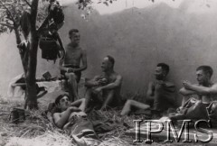 22.06.1941, brak miejsca.
I Dywizja Strzelców Górskich - odpoczynek. Żołnierze w niepełnym umundurowaniu rozmawiają oraz spożywają posiłek. Na drzewie zawieszone zostały poszczególne elementy wojskowego ekwipunku. Orginalny podpis w języku niemieckim: 