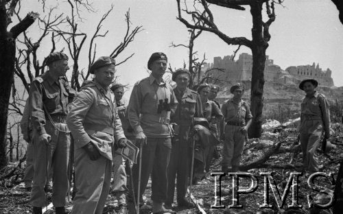 Maj 1944, Cassino, Włochy.
Generał Władysław Anders zwiedza pobojowisko w towarzystwie oficerów ze Sztabu. W głębi widać ruiny klasztoru na górze Monte Cassino. Generał i świta idą drogą oczyszczoną przez saperów 3 Dywizji Strzelców Karpackich. Droga jest oznaczona białą taśmą. 
Fot. Felicjan Maliniak, Instytut Polski im. Gen. Sikorskiego w Londynie [album negatywowy L-I Monte Cassino] - płachta 46