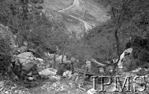 Maj 1944, Cassino, Włochy.
Sanitariusze z flagą Czerwonego Krzyża zbierający rannych z pola bitwy, w tle droga na górskim zboczu.
Fot. Felicjan Maliniak, Instytut Polski im. Gen. Sikorskiego w Londynie [album negatywowy L-I Monte Cassino] - płachta 49