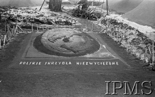 Grudzień 1941, Kołtubanka, obł. Czkałowsk, ZSRR.
Obóz formującej się Armii Andersa, płaskorzeźba na ziemi - orzeł z rozpostarymi skrzydłami - symbol 2 Eskadry Lotniczej. Na ziemi napis: 