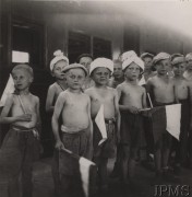 1942, Indie.
Ewakuacja polskich sierot ze Związku Radzieckiego. Grupa dzieci z chorągiewkami stoi na tle pociągu. Podpis: 