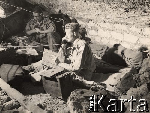 Wiosna 1944, Cassino, Włochy.
Bitwa pod Monte Cassino. Punkt dowodzenia, w środku siedzi oficer brytyjski z mapą i słuchawką telefonu w ręku, za nim siedzi radiotelegrafista. Pod ścianą leży śpiący żołnierz.
Fot. NN, zbiory Instytutu Józefa Piłsudskiego w Londynie
