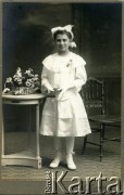 Pocz. XX wieku, Düsseldorf, Niemcy. 
Portret dziewczynki w białym stroju komunijnym, z modlitewnikiem w ręku. Zdjęcie wykonane w atelier fotograficznym 