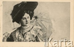 Pocz. XX wieku, Paryż, Francja.
Portret kobiety we wzorzystej sukni, z kapeluszem na głowie i naszyjnikiem białych pereł na szyi. Kobieta w dłoni trzyma jasną parasolkę. Zdjęcie wykonane w atelier fotograficznym. Kartka sygnowana nazwiskiem fotografa 