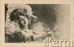 Pocz. XX wieku, Paryż, Francja.
Portret kobiety w jasnej sukni balowej, z ozdobnym kapeluszem. Kobieta w pozycji do tańca, z wyciągniętymi przed siebie rękoma. Zdjęcie wykonane w atelier fotograficznym.  Kartka sygnowana nazwiskiem fotografa 
