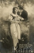 Lata 20., Niemcy.
Portret zakochanej pary - kobiety w jasnej sukni, trzymającej bukiet kwiatów oraz mężczyzny w ciemnej marynarce i białej koszuli. Zdjęcie wykonane w atelier fotograficznym. Na karcie napis w języku niemieckim: 