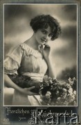 Ok. 1918, Niemcy.
Portret kobiety w białej sukni, trzymającej w dłoni bukiet kwiatów. Zdjęcie wykonane w atelier fotograficznym. Napis pod zdjęciem w języku niemieckim: 