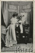 Pocz. XX wieku, Francja.
Portret kobiety w długiej jasnej sukni i mężczyzny. Kobieta zasłania mężczyźnie oczy podczas zabawy. Pod fotografią podpis w języku francuksim: 