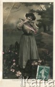 1907, Francja.
Portret kobiety, trzymającej w ramionach rybę. Zdjęcie wykonane w atelier fotograficznym. U dołu napis w języku francuskim 