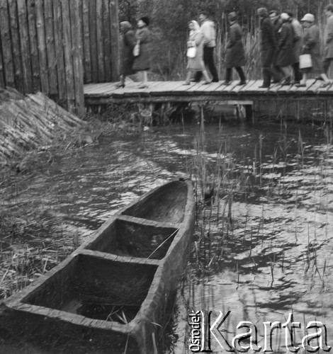 1960, Biskupin, Polska.
Turyści zmierzają do osady Biskupin. Na pierwszym planie drewniana łódka dryfująca na jeziorze.
Fot. Jerzy Konrad Maciejewski, zbiory Ośrodka KARTA.